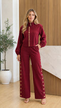 Front view of model wearing burgundy stand collar top and wide-leg pants set with gold hardware
