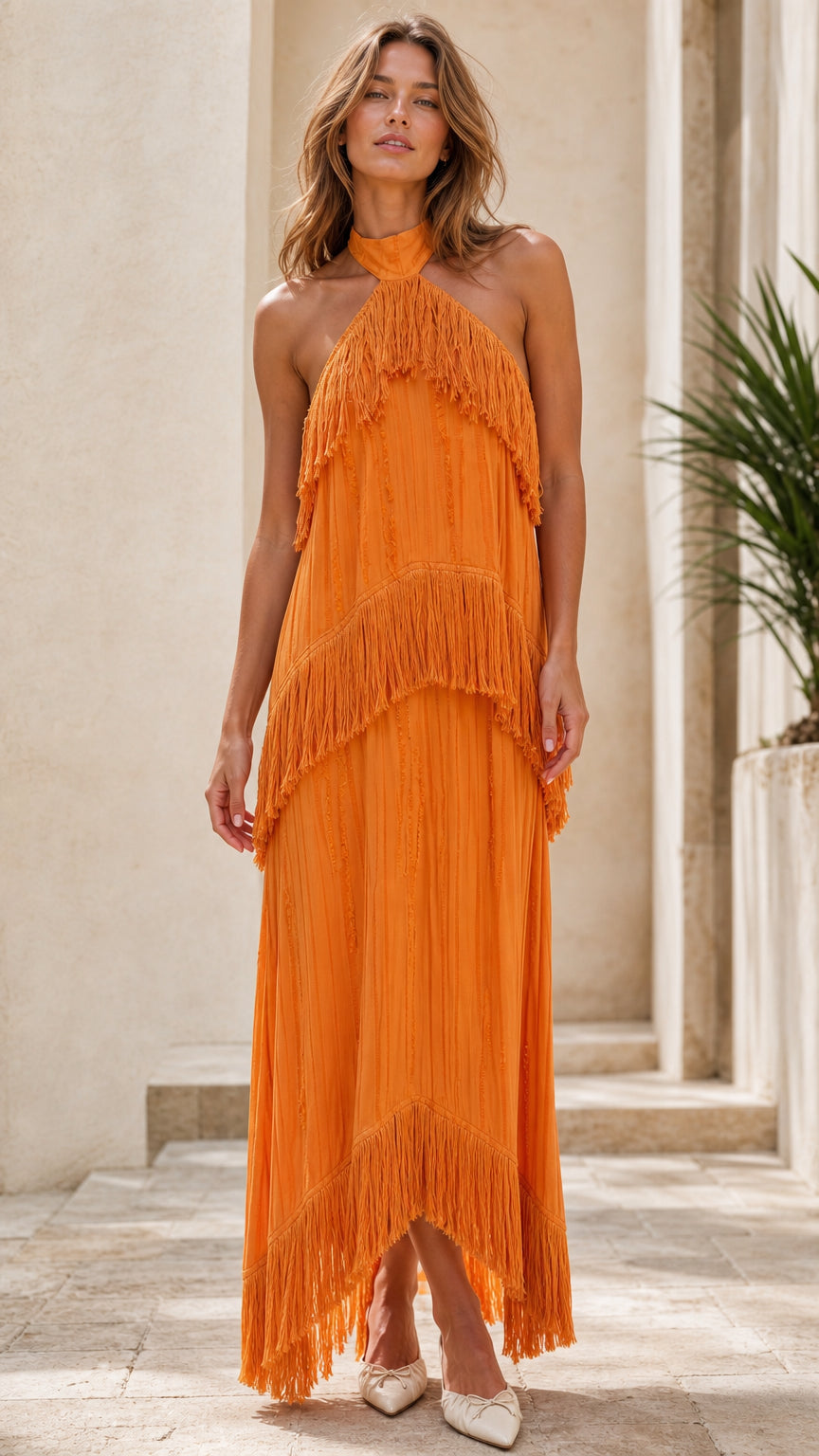 Model wearing bright orange halter neck tiered fringe maxi dress from the front
