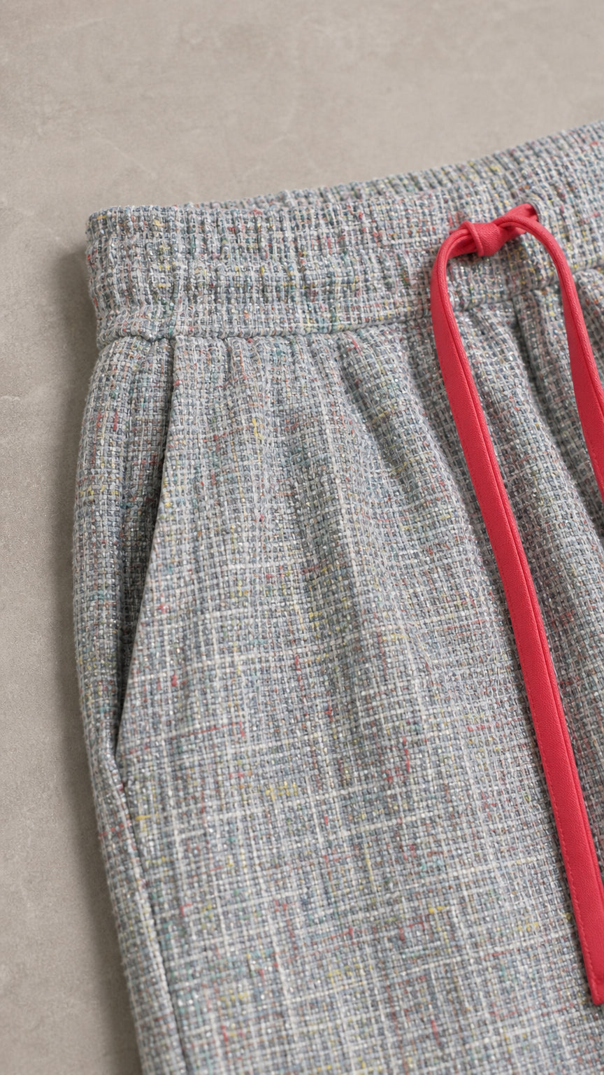 Close-up of the elastic waistband and drawstring detail on light grey pants