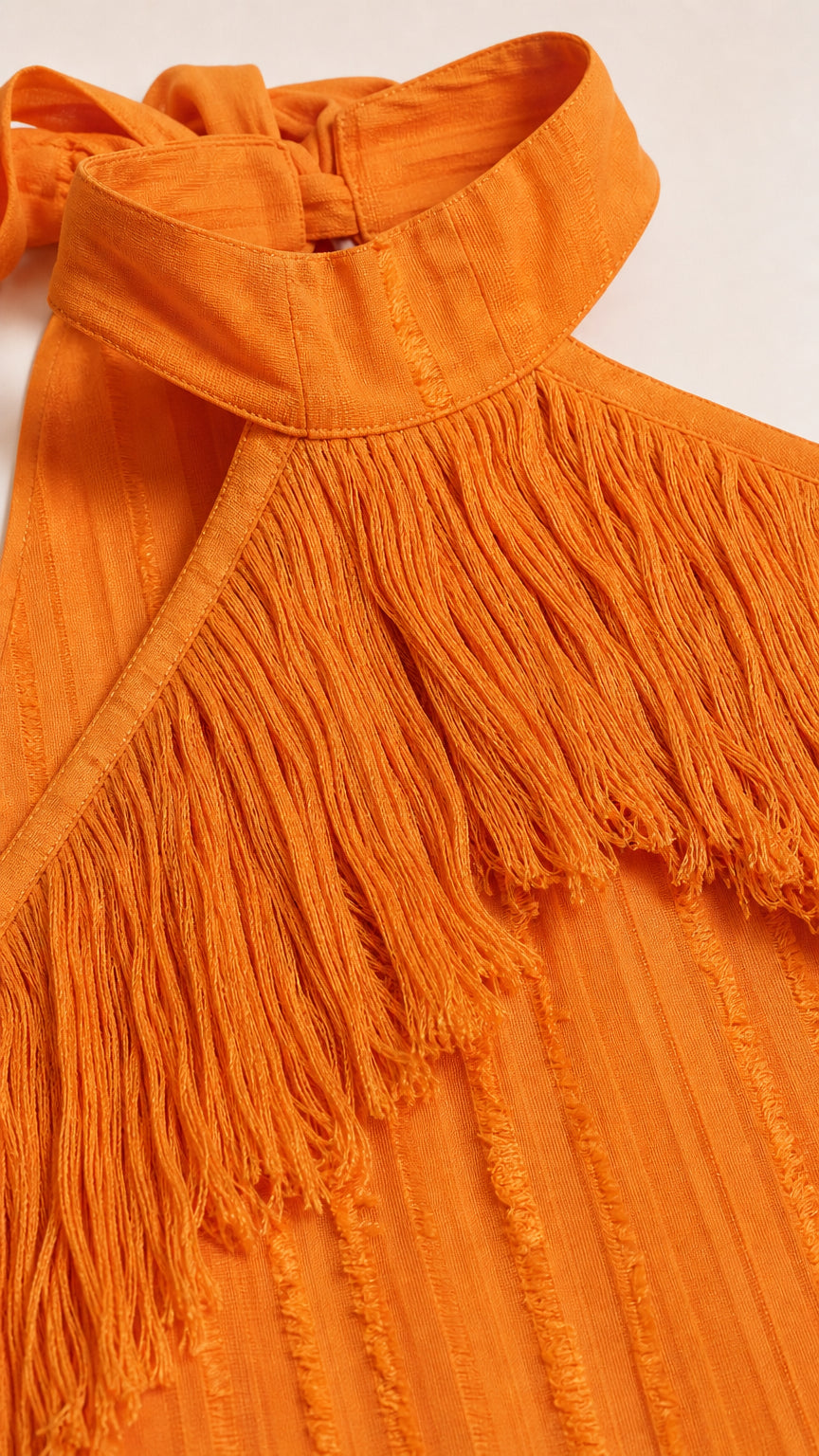 Close-up detail of the halter neckline and fringe texture in orange