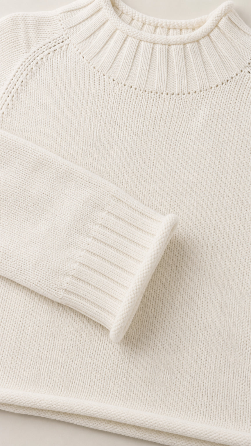 Close-up detail of white knit sweater collar and ribbed sleeve cuff