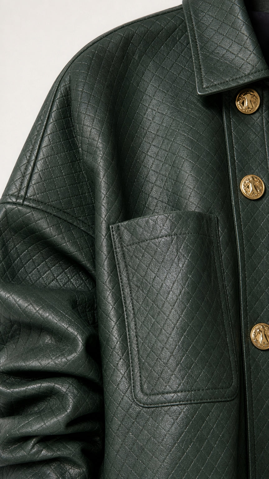 Close-up detail of dark green quilted faux leather texture, pocket, and metallic buttons